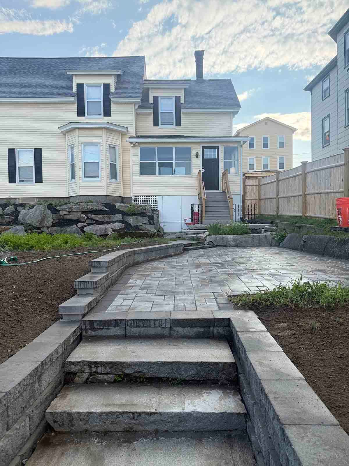 Front yard stone steps and walkway leading to a white house with a front porch and stone retaining walls.