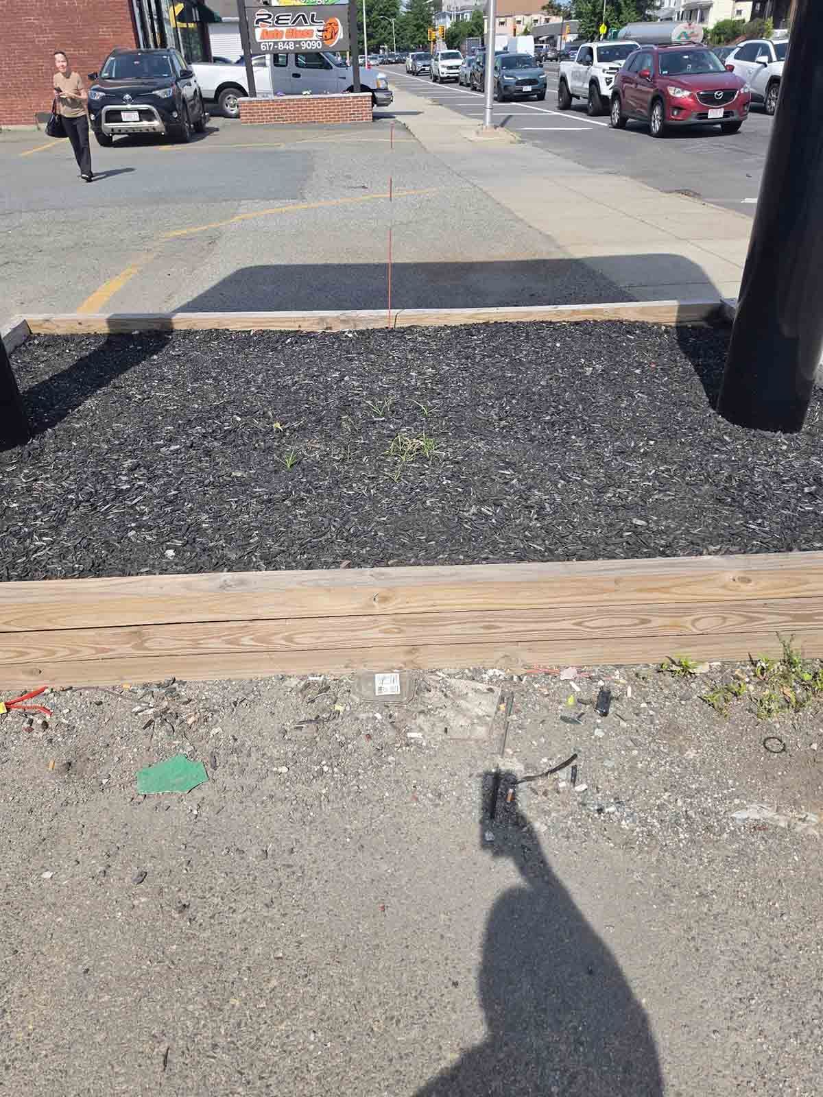Street curb ramp with tactile paving and a sidewalk crossing, viewed from the lower landing.