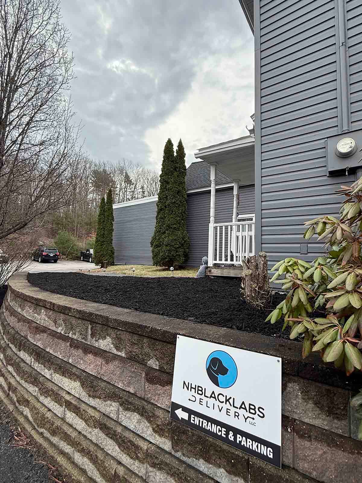 HealthLabs sign outside a gray building with a landscaped stone wall and tall shrubs.