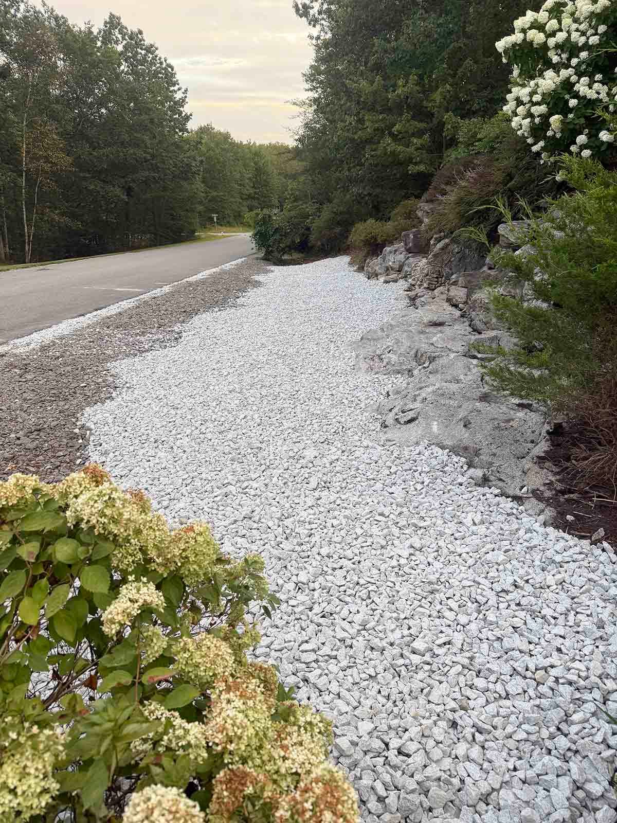 Rocky roadside embankment covered in white gravel beside a winding forest road