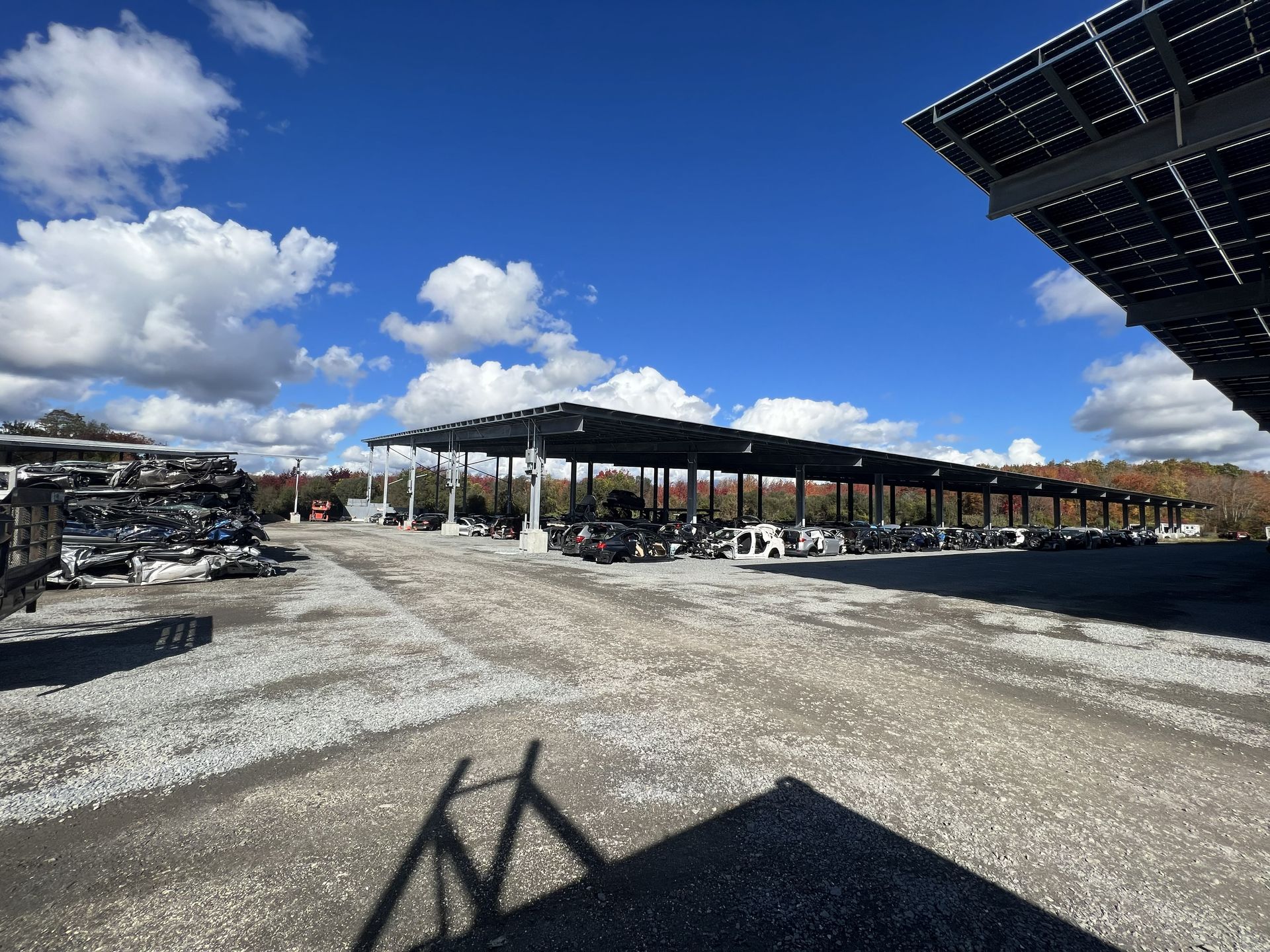 Solar panels cover a parking area with parked cars on a sunny day.