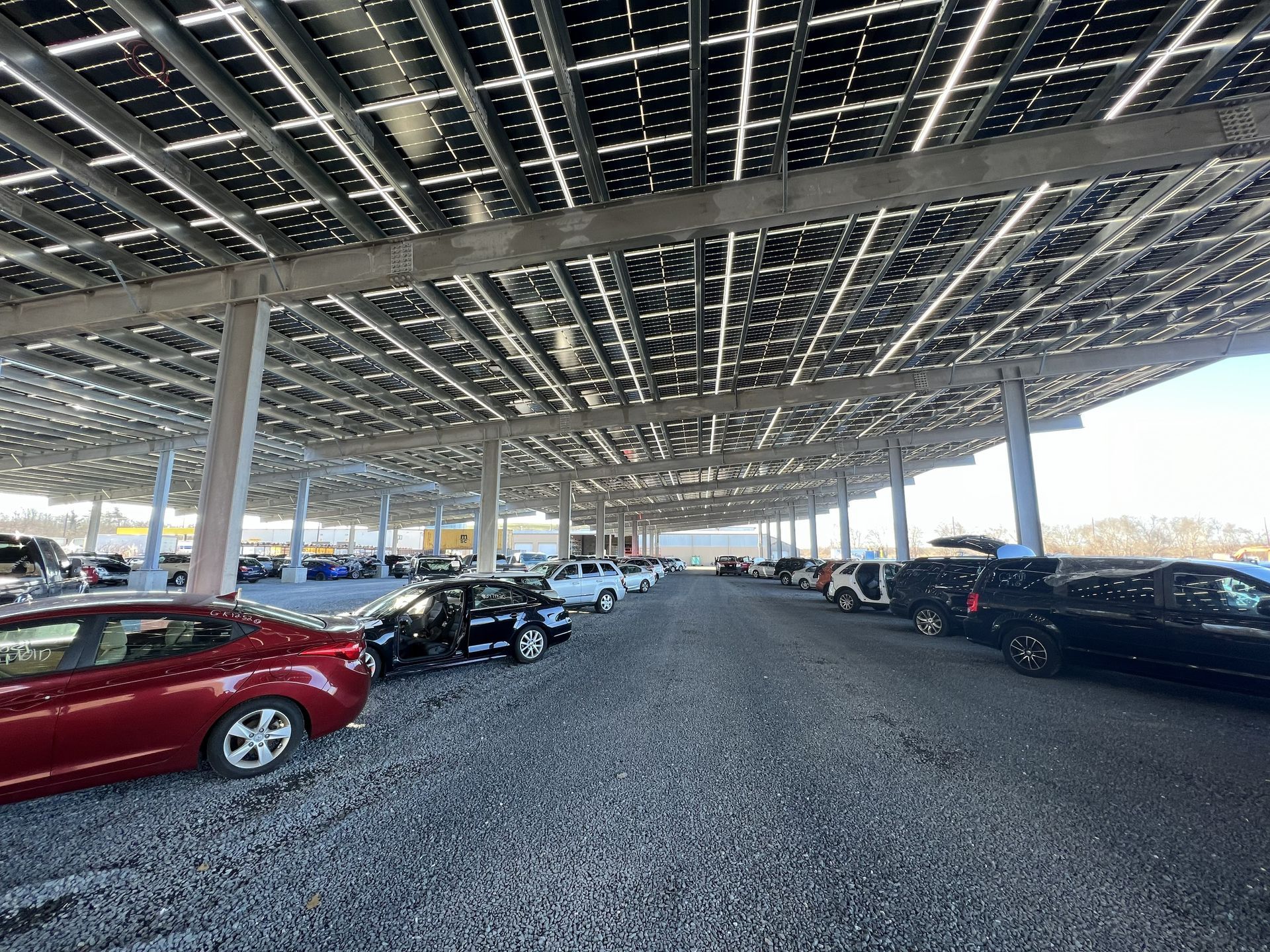 Parking lot covered by solar panels, with rows of cars parked underneath.