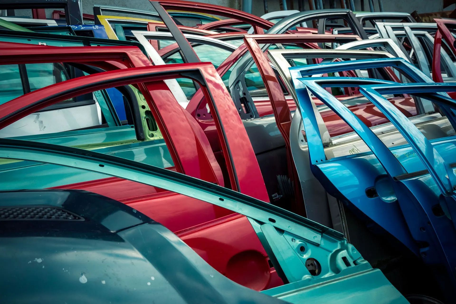 Scrap yard filled with colorful car doors in various shades of red, blue, and teal.