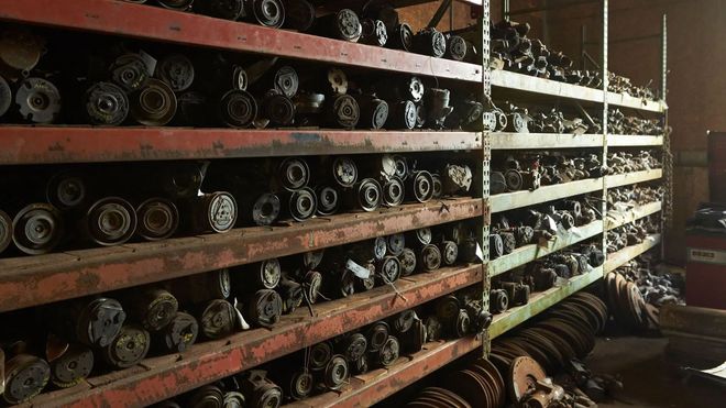 Shelves filled with used truck parts in a warehouse setting.