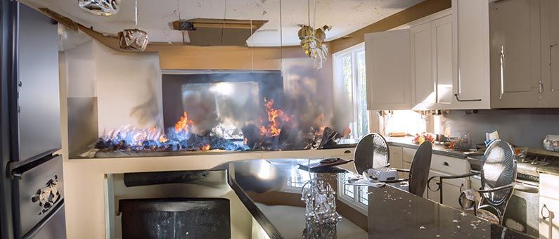 Kitchen engulfed in flames, with fire spreading across the countertop and cabinets