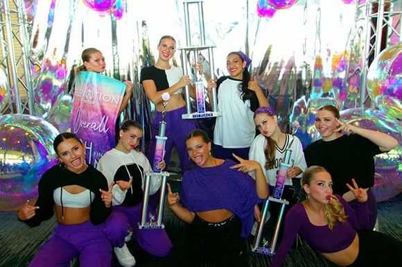 A group of young women are posing for a picture while holding trophies.