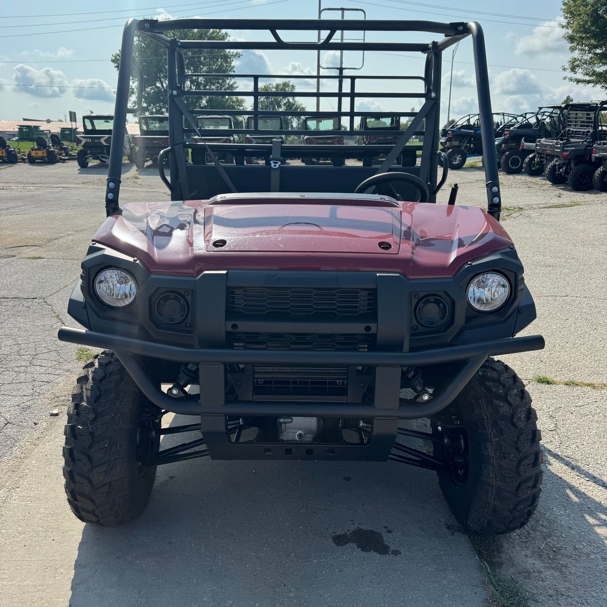 Front view of a red off-road utility vehicle with roll cage, parked on a lot.
