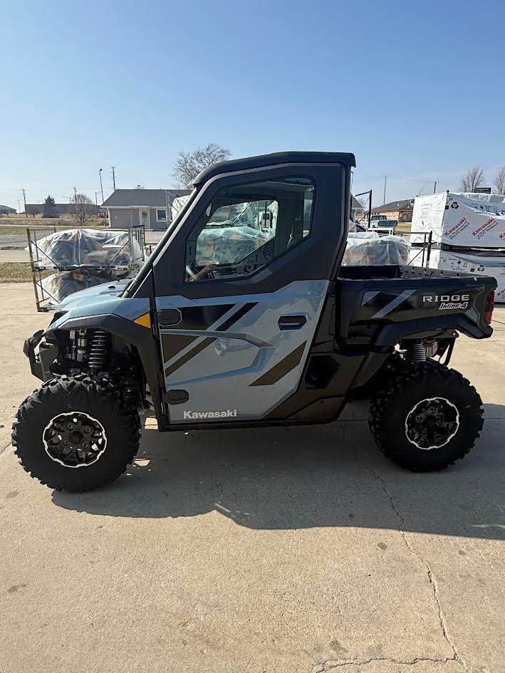 Side-view of a black and gray UTV parked on a concrete lot in bright sunlight