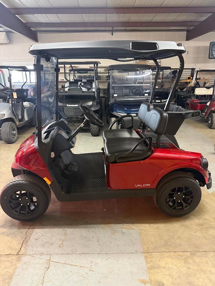 Red golf cart with black roof and seats parked inside a garage.