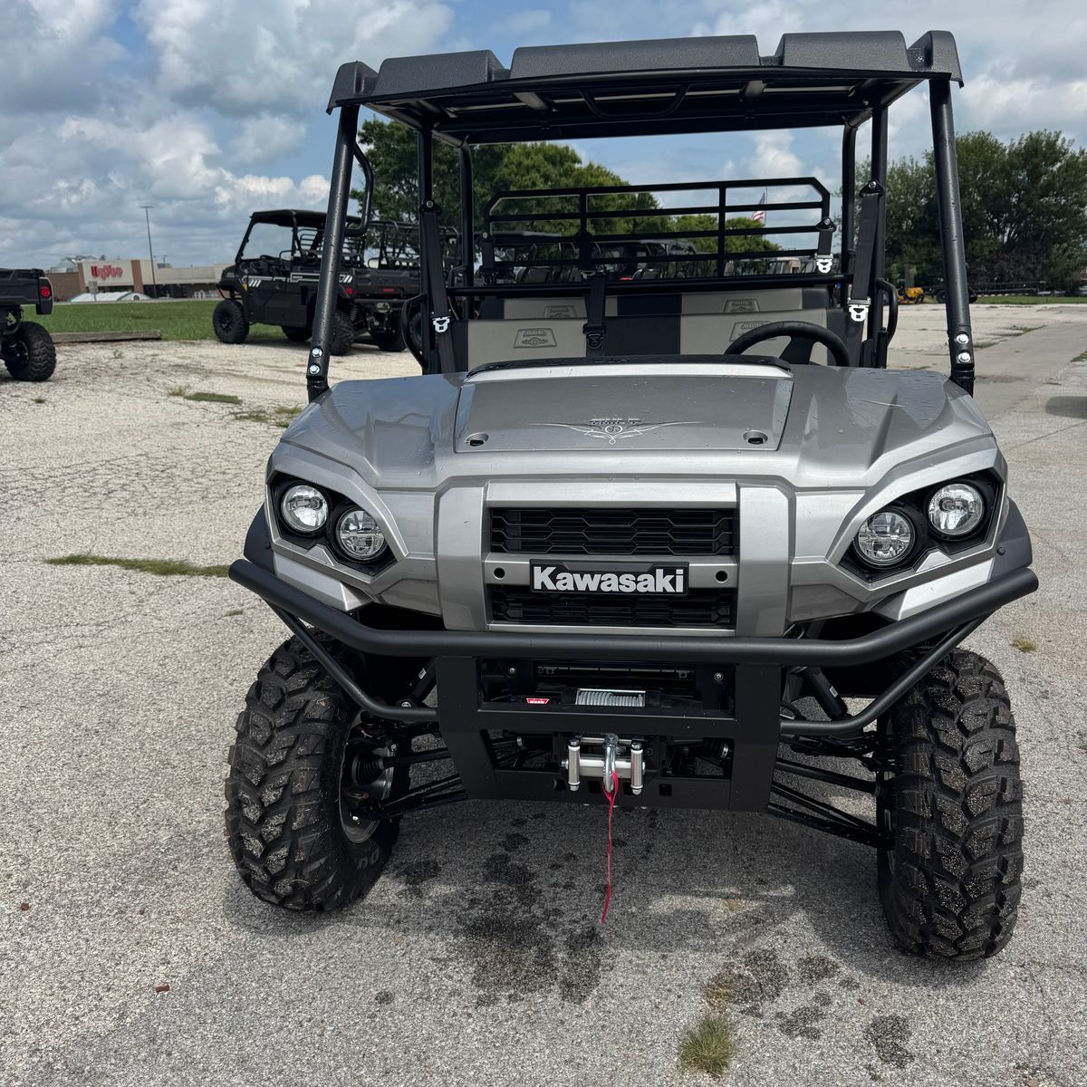 Front view of a gray Kawasaki UTV with off-road tires parked on gravel outdoors