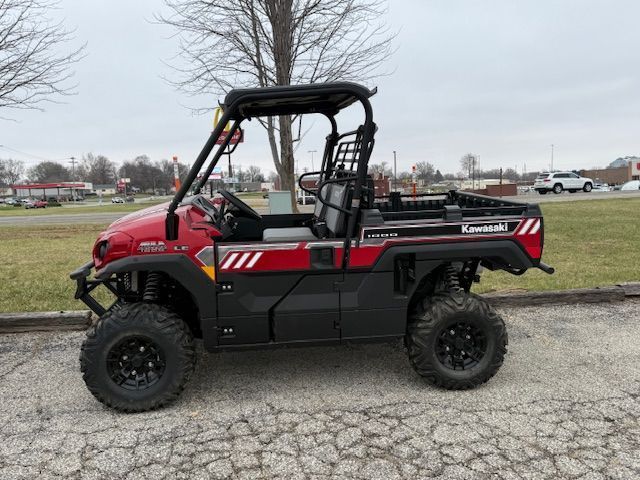 Red and black side-by-side off-road utility vehicle parked on pavement near a grassy field.