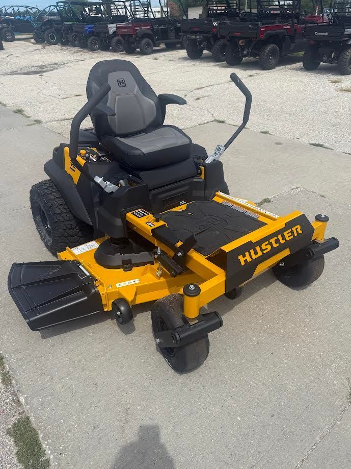 Black and yellow Hustler riding lawn mower parked on pavement