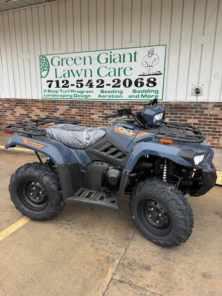 Black ATV parked outside Green Giant Lawn Care sign on a wet driveway