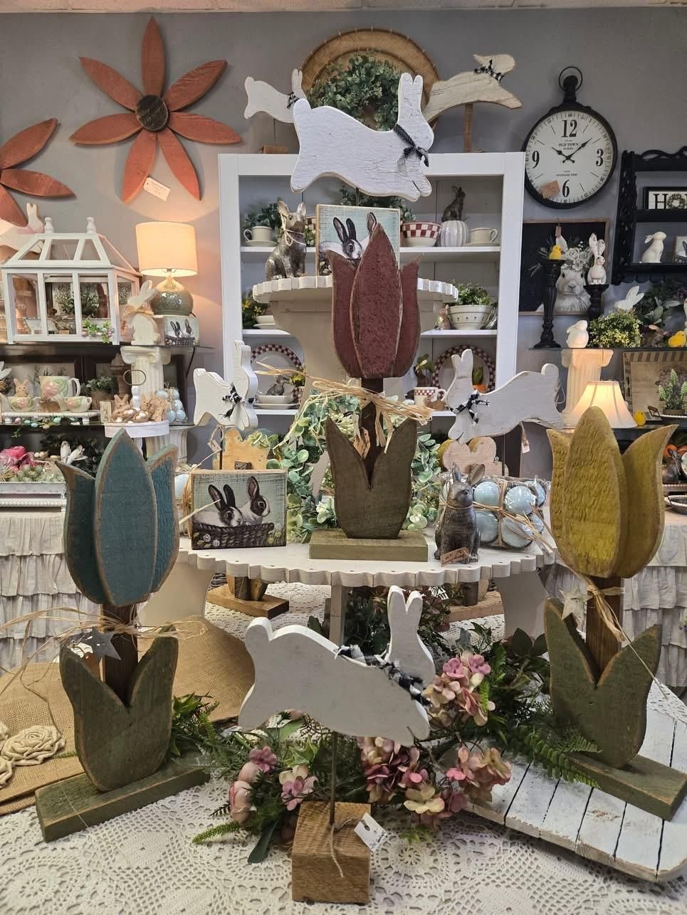 A display of wooden flowers and rabbits in a room with a clock on the wall