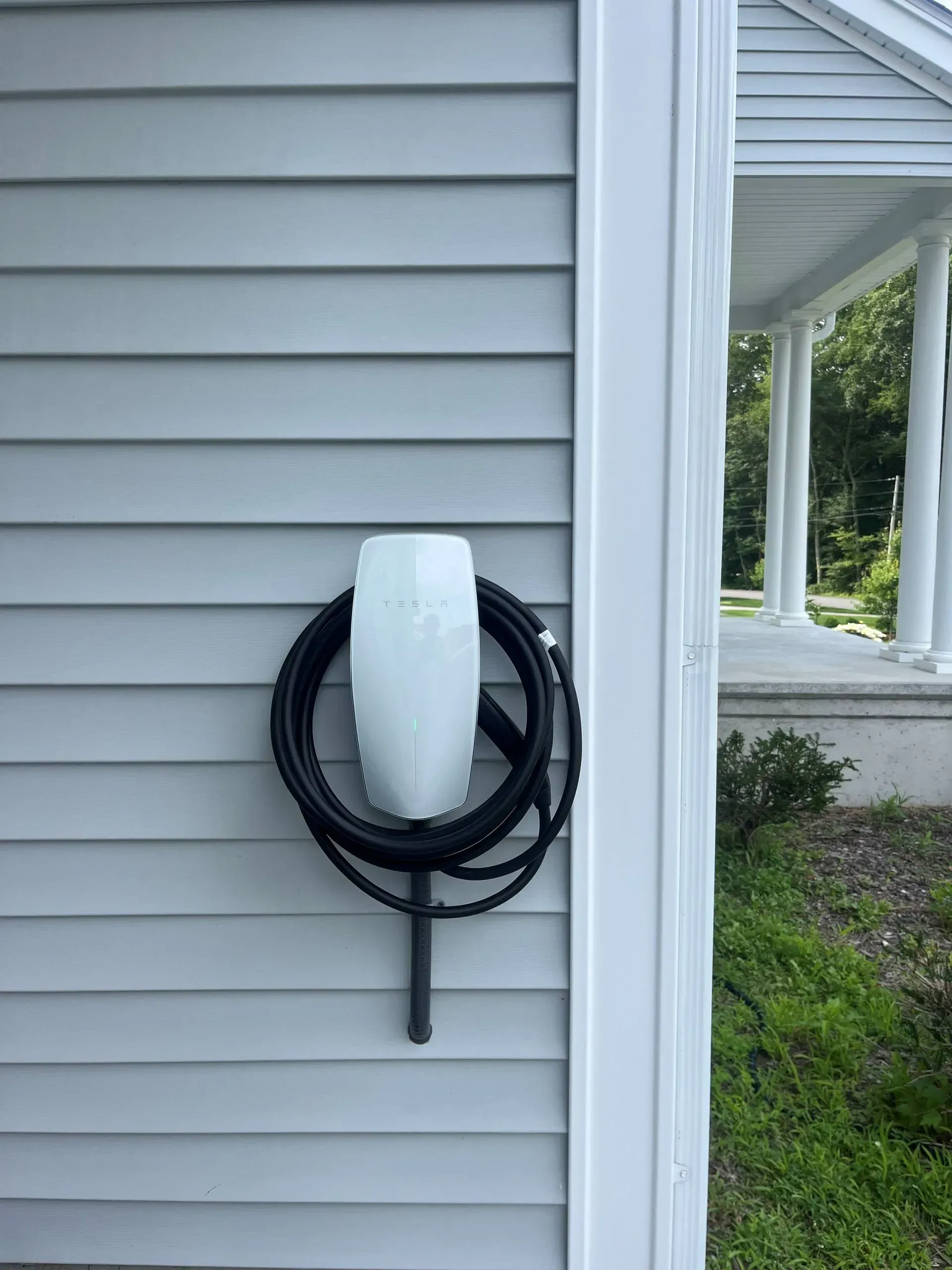 A tesla charging station is attached to the side of a house.