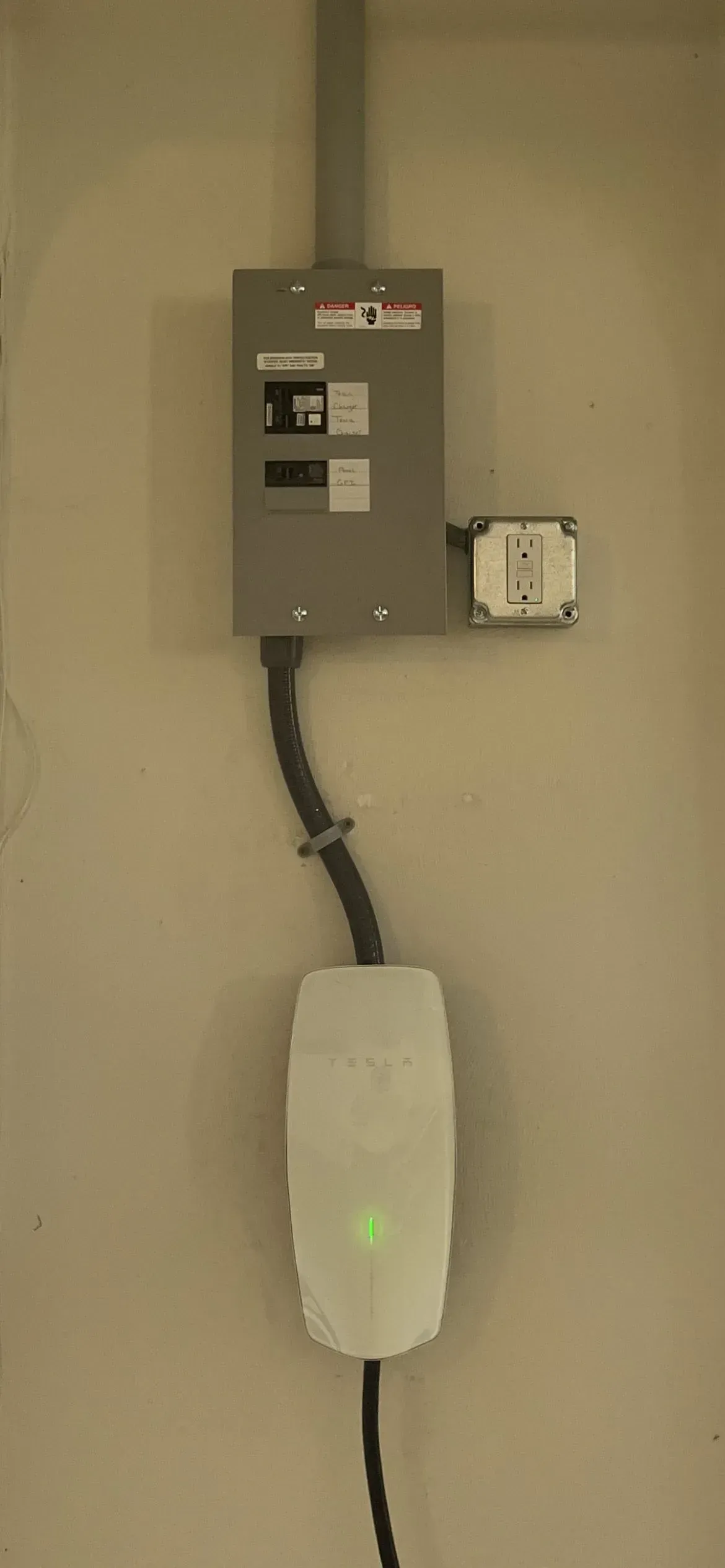 A white electric vehicle charger is attached to a wall.