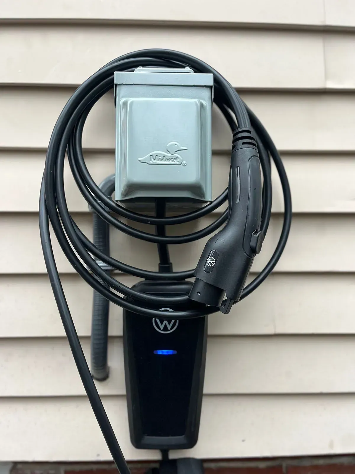 A car charger is attached to the side of a house.