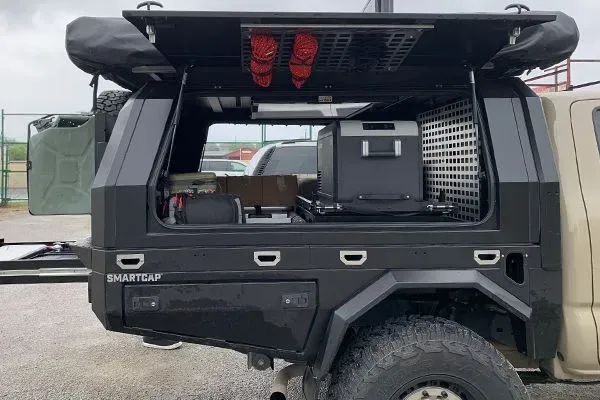 Black off-road truck with open canopy and rooftop gear, showing a storage setup in the back.