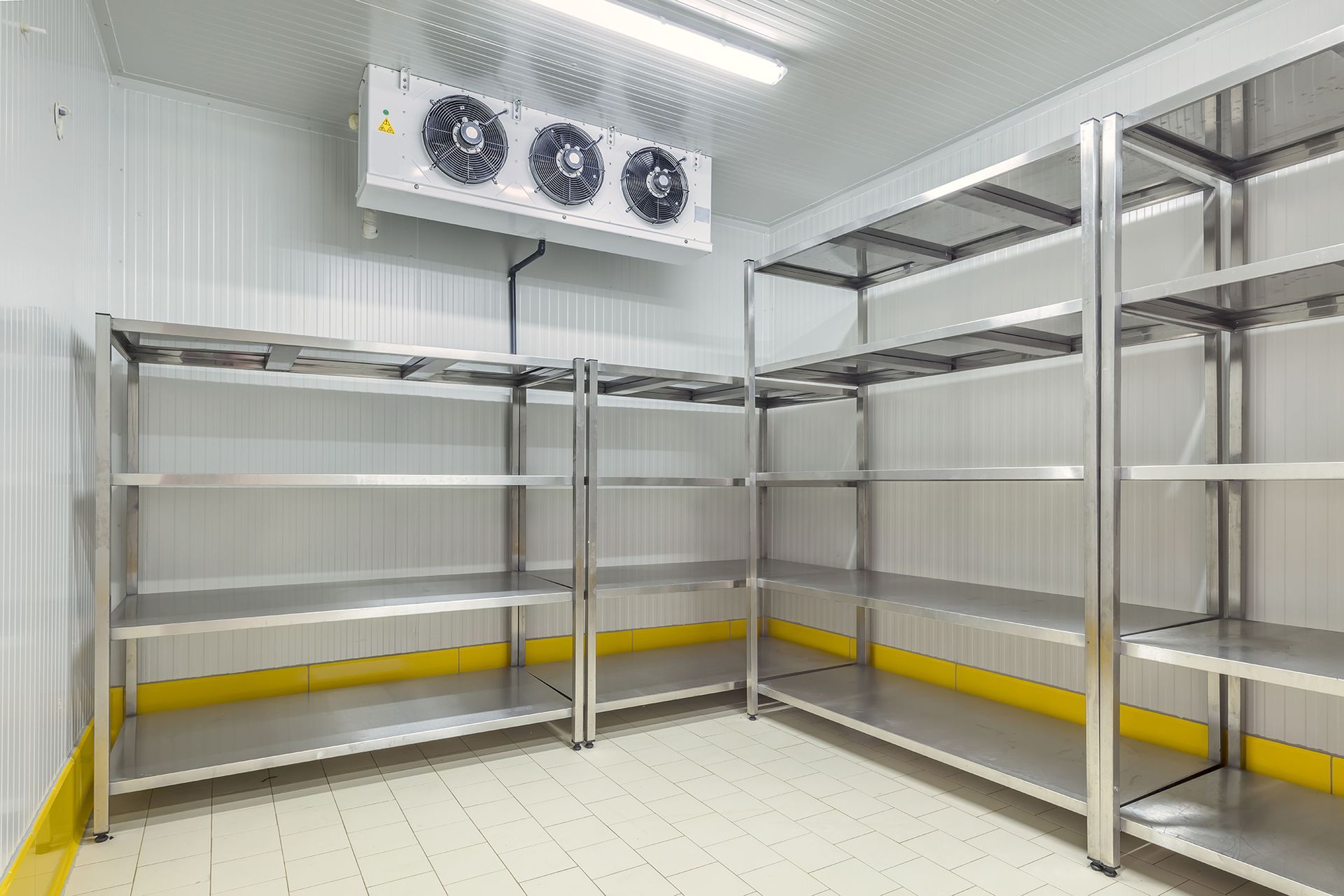 Inside a commercial refrigerator: stainless steel shelves and cooling unit on the wall.