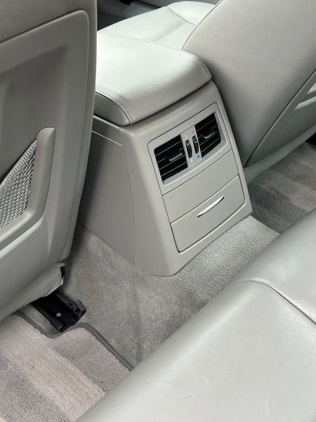 The light gray interior of a vehicle showing the back of the center console, including air vents and a small drawer.