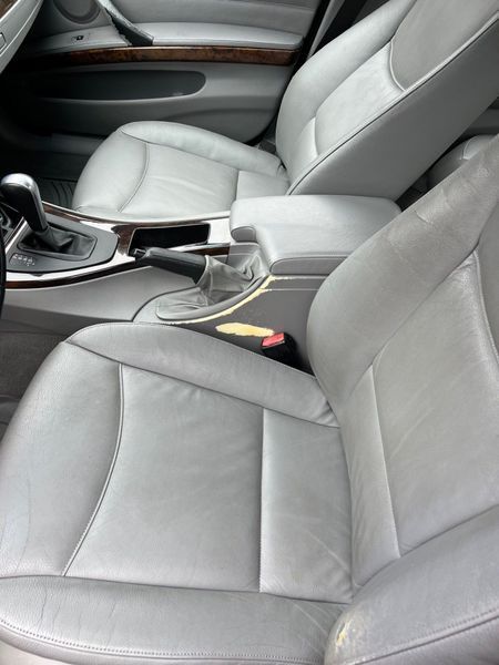 The light gray leather interior of a car, showing the front seats, center console, gear shifter, and wood grain trim.