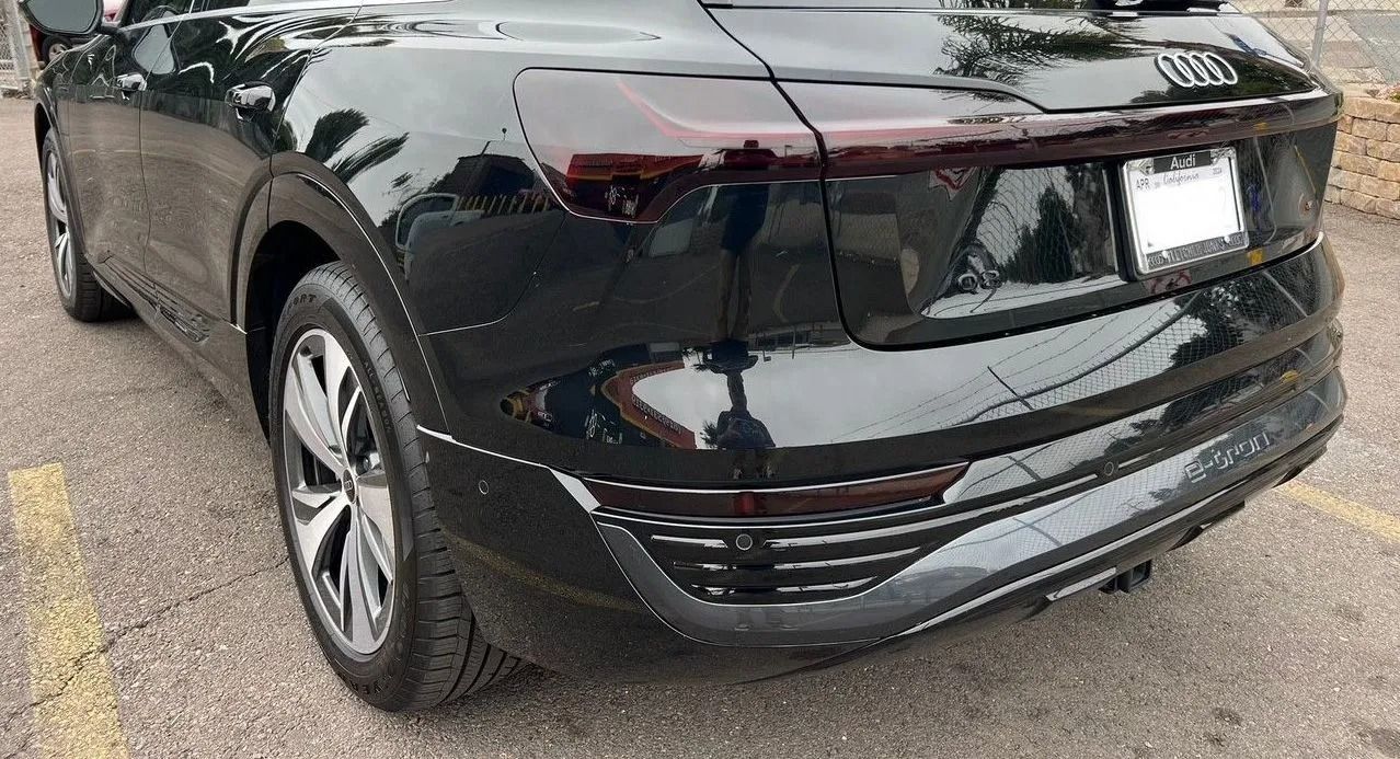 A rear three-quarter view of a black Audi SUV parked on an asphalt lot.