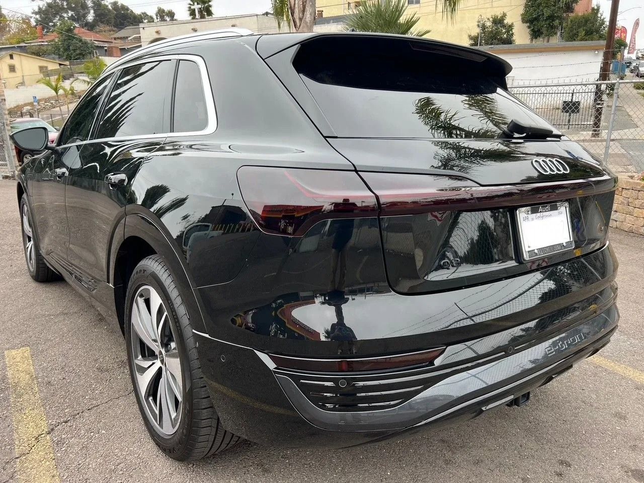 A black Audi e-tron SUV parked in a paved outdoor lot, viewed from the rear three-quarter angle.