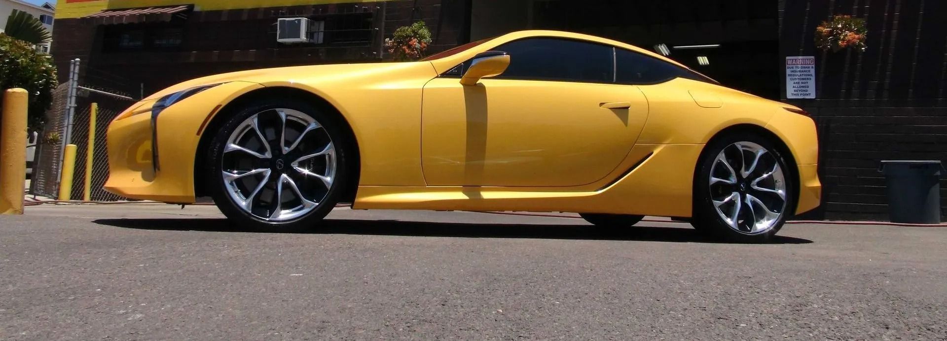 A side view of a bright yellow Lexus LC coupe parked on asphalt.