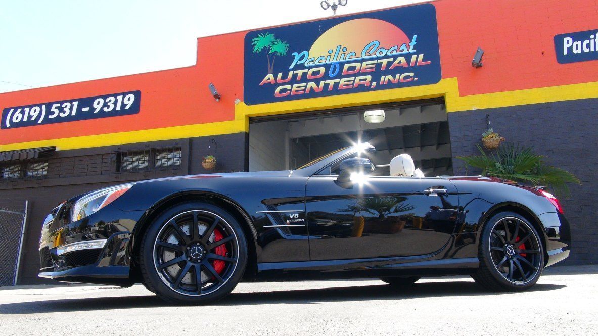 A black convertible car parked in front of the Pacific Coast Auto Detail Center building.