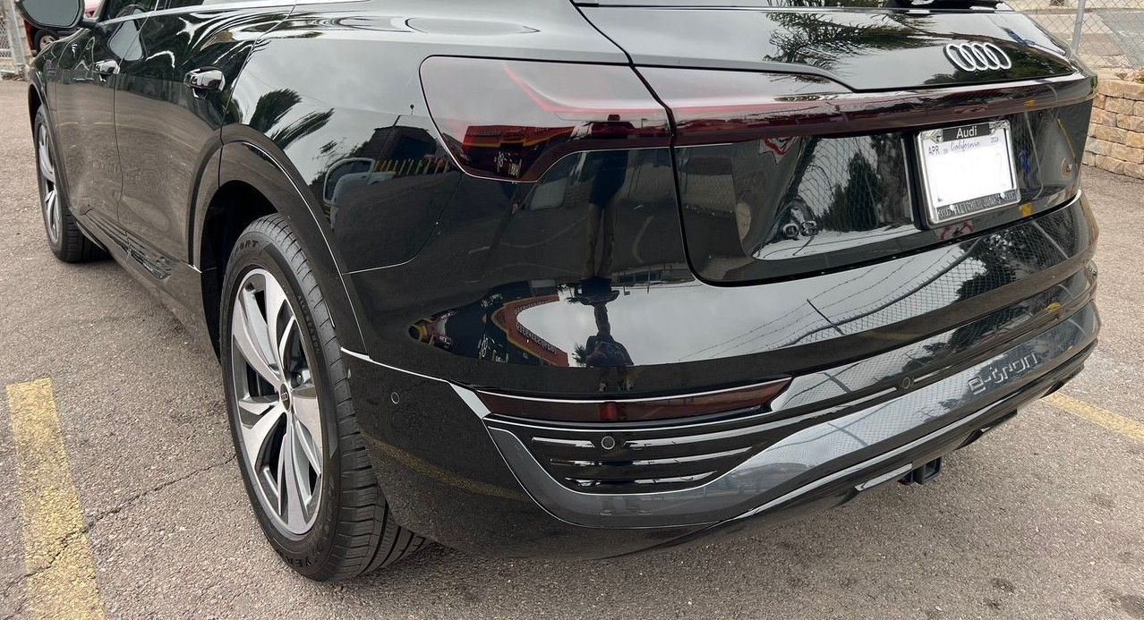 A close-up, rear three-quarter view of a black Audi SUV parked on an asphalt lot.