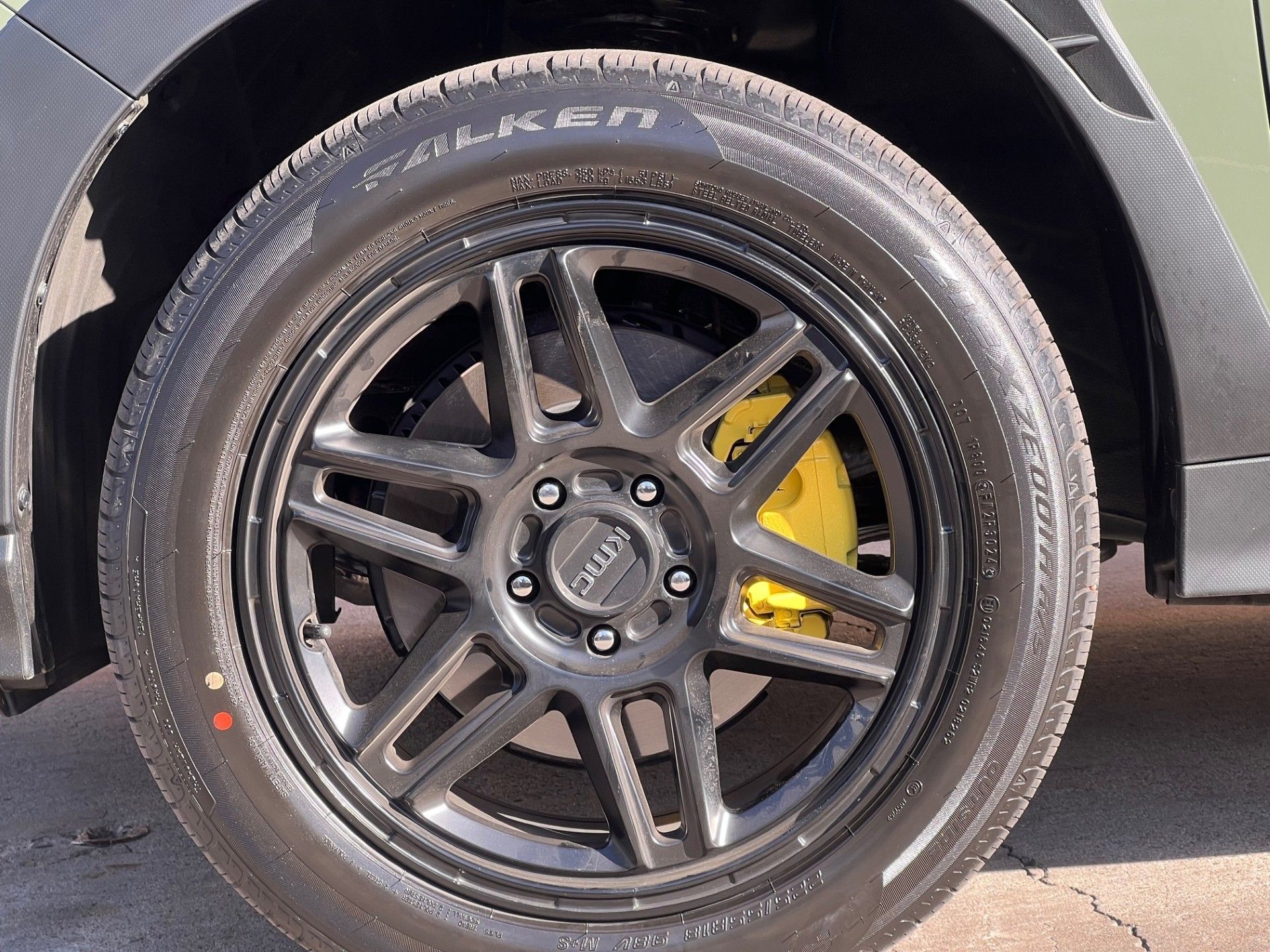 A close-up of a matte black car wheel with Falken tires and a bright yellow brake caliper.