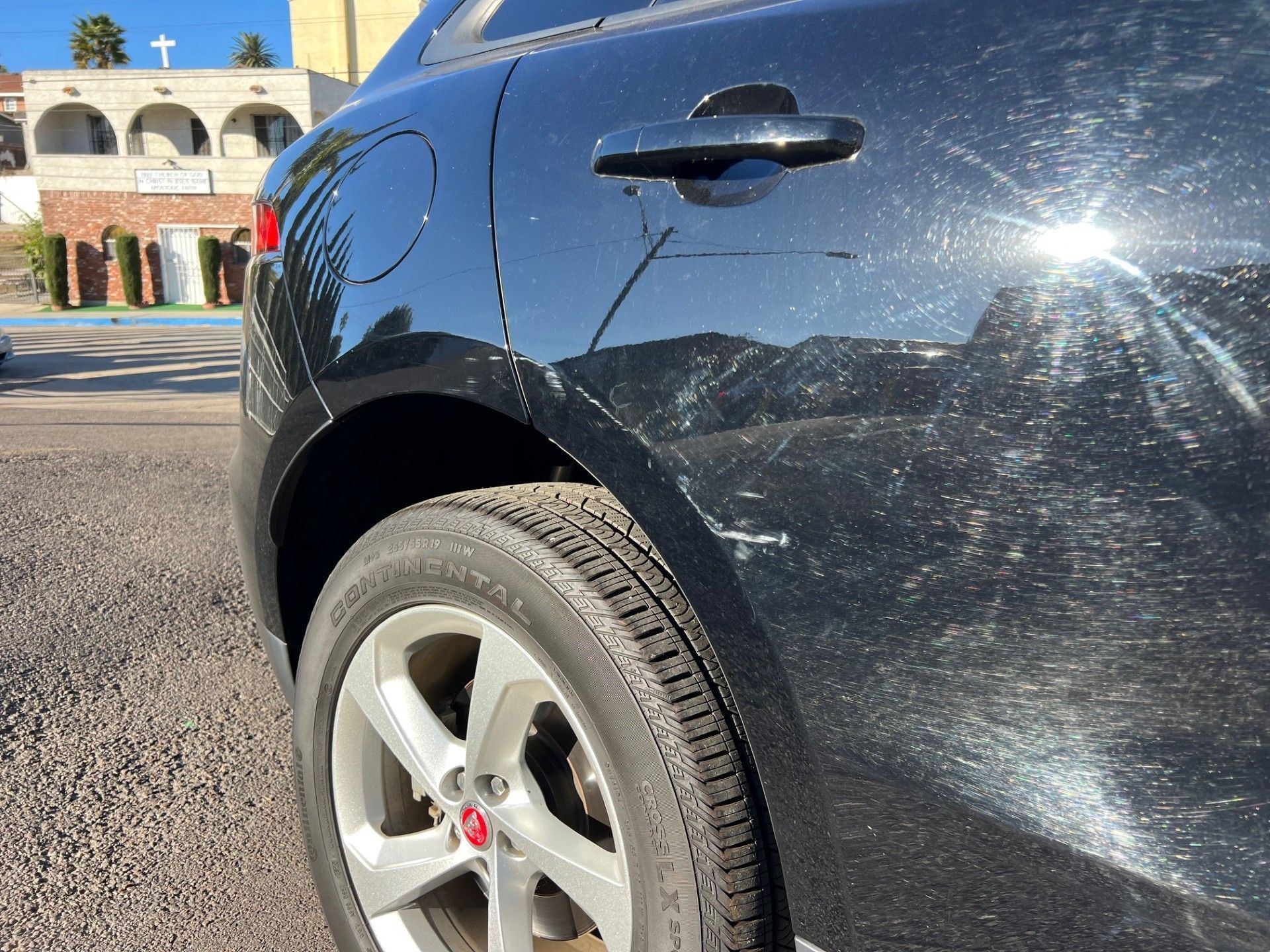 A black Jaguar SUV showing paint scratches on the rear quarter panel and door near the wheel and handle.
