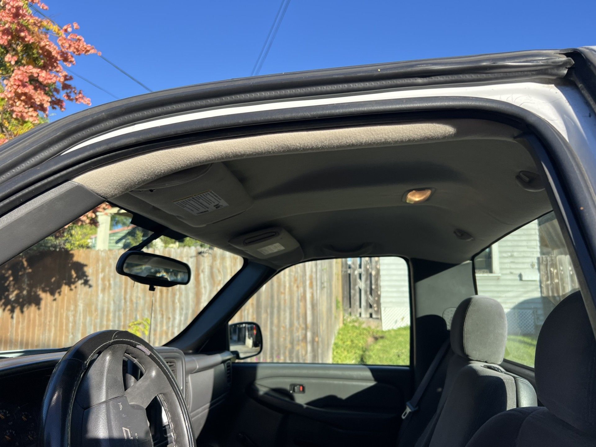 Interior view of a vehicle cabin looking toward the windshield, rearview mirror, headliner, and passenger side seating.