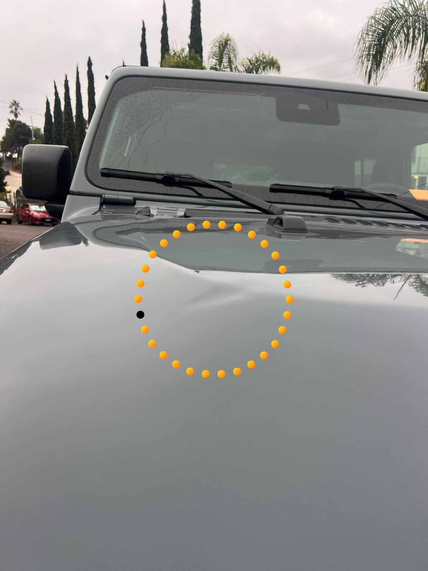 A light gray Jeep hood with a visible dent, indicated by a yellow dotted circle.