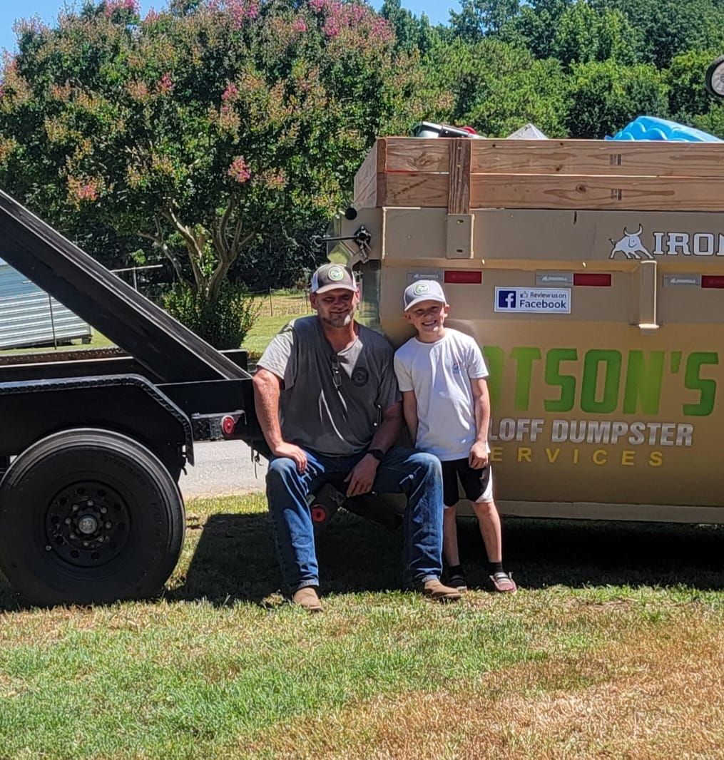 Two men are sitting on the back of a dumpster.