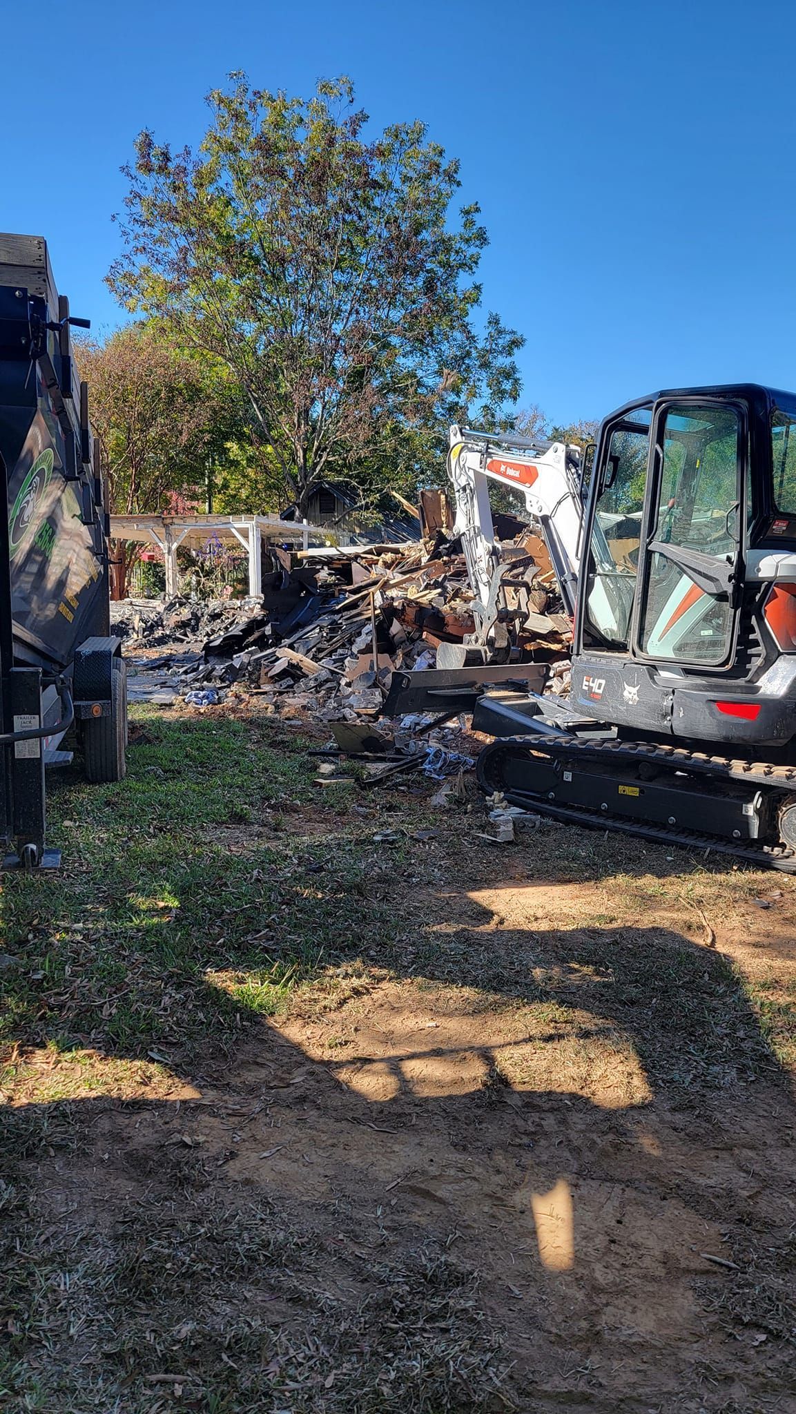 A bulldozer is demolishing a house in a yard.