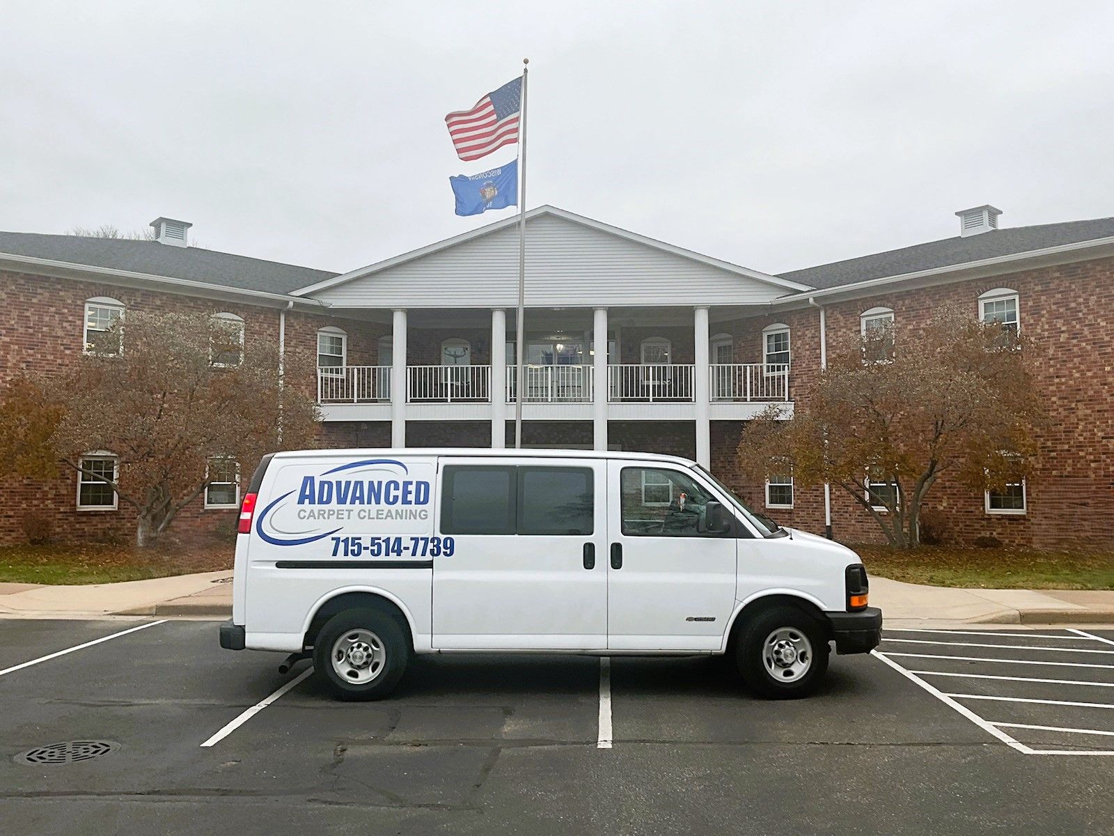 A white van is parked in front of a large building