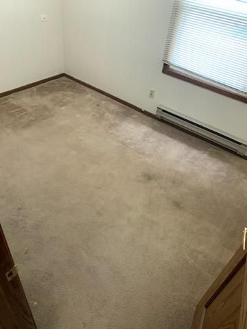 A bedroom with a carpeted floor and a window.