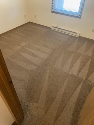 A bedroom with a clean carpeted floor and a window.