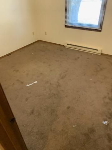 An empty room with a carpeted floor and a window.