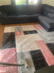 A living room with a sectional couch and a clean rug.