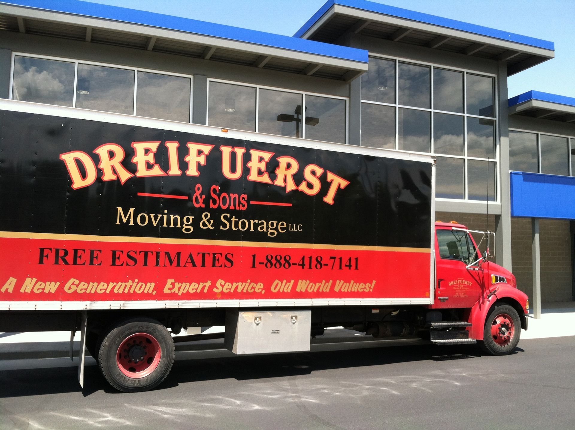 Red Dreifuerst & Sons moving truck in front of a modern building with large windows.