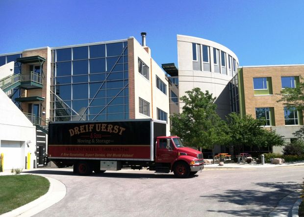 Red delivery truck parked in front of modern building. Truck says "DREIFUERST". Sunny day.