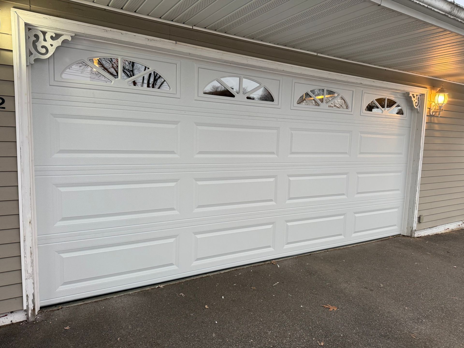 White garage door with arched glass windows and decorative trim.