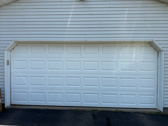 White garage door on a white sided building.