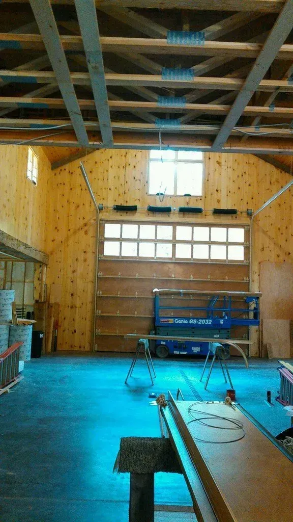 Interior view of a wooden workshop with a closed large door and a lift in front of it.