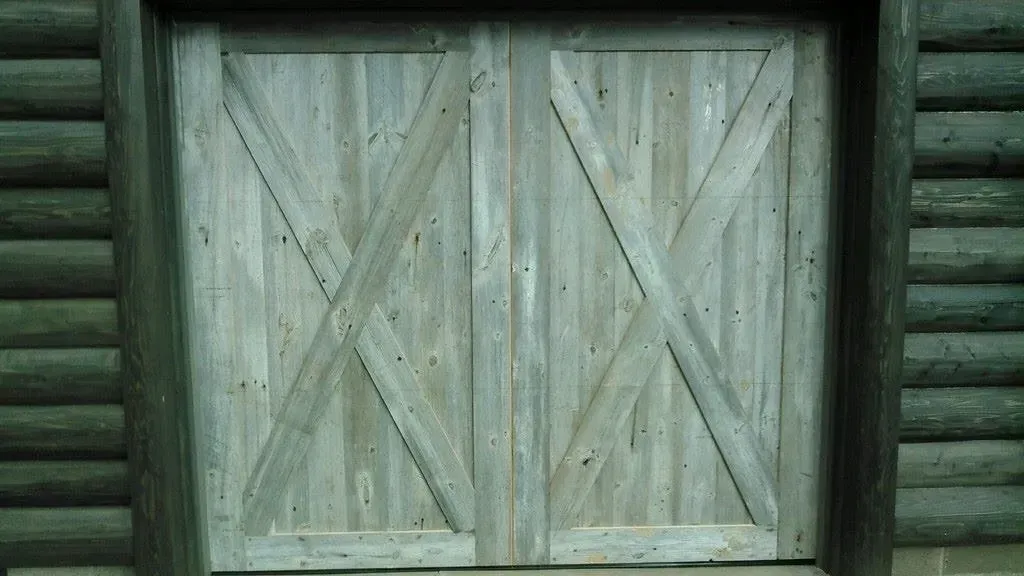 Weathered wooden double doors on a log cabin wall.