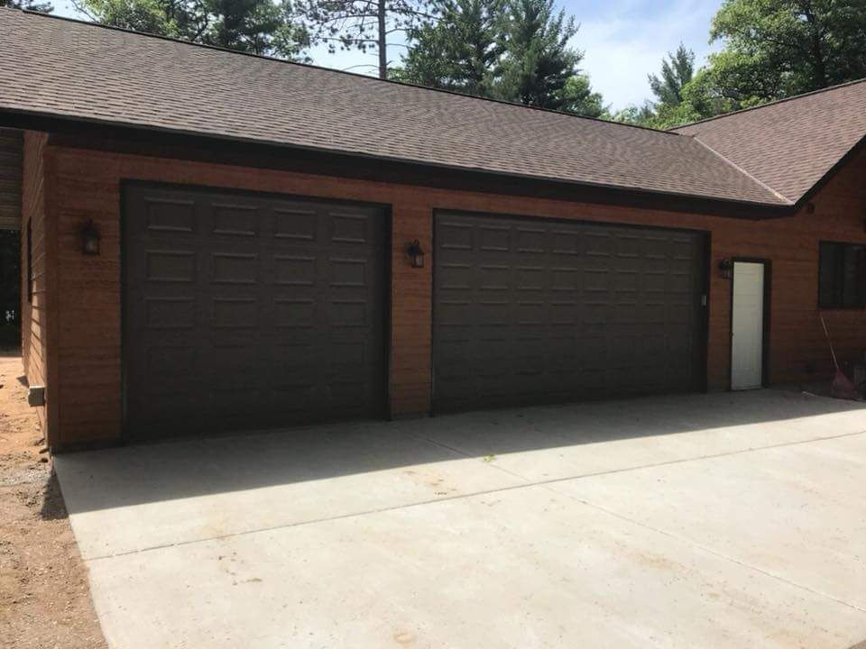 Brown garage doors on a brown-sided building with concrete driveway.