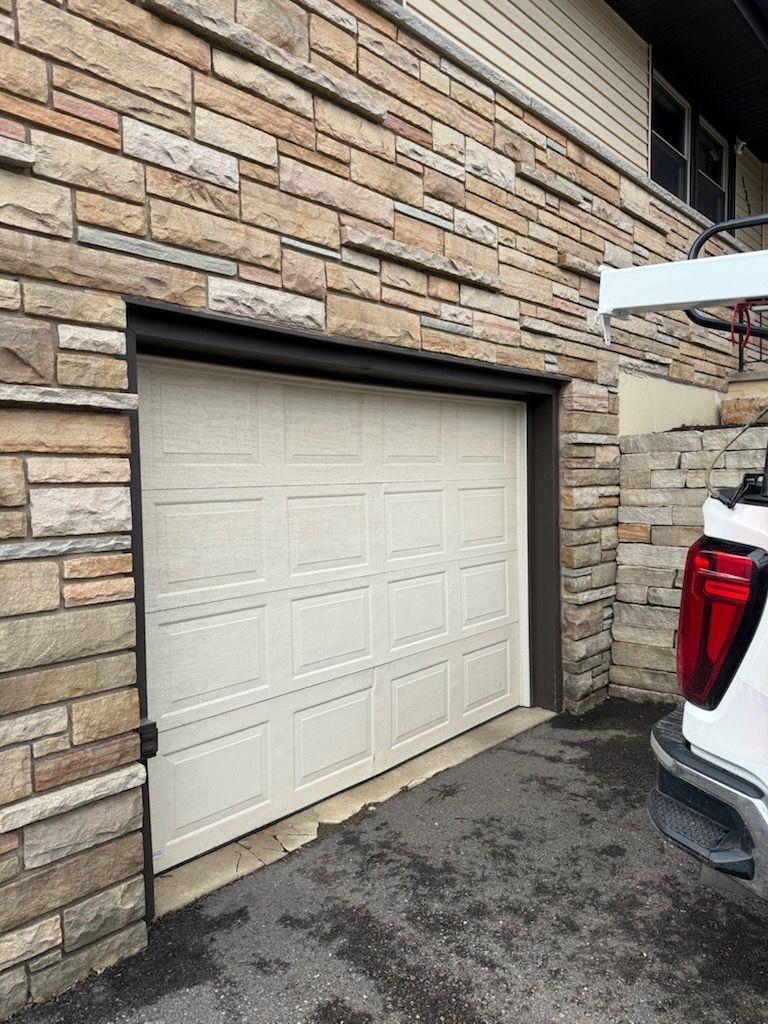 White garage door in a stone building facade, partially open.
