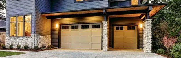 Exterior view of a modern house with two garage doors and a covered entryway.